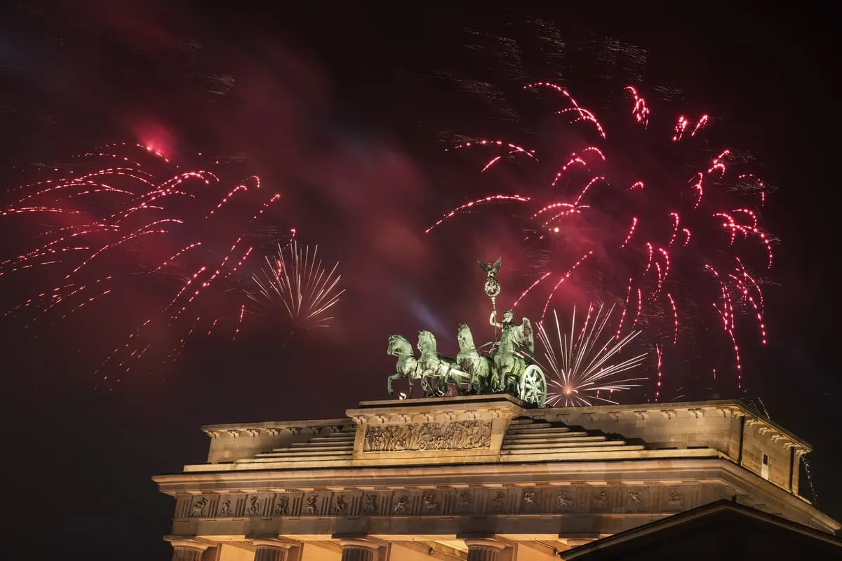 Red fireworks exploding behind the Quadriga statue on top of the Brandenburg Gate in Berlin at night